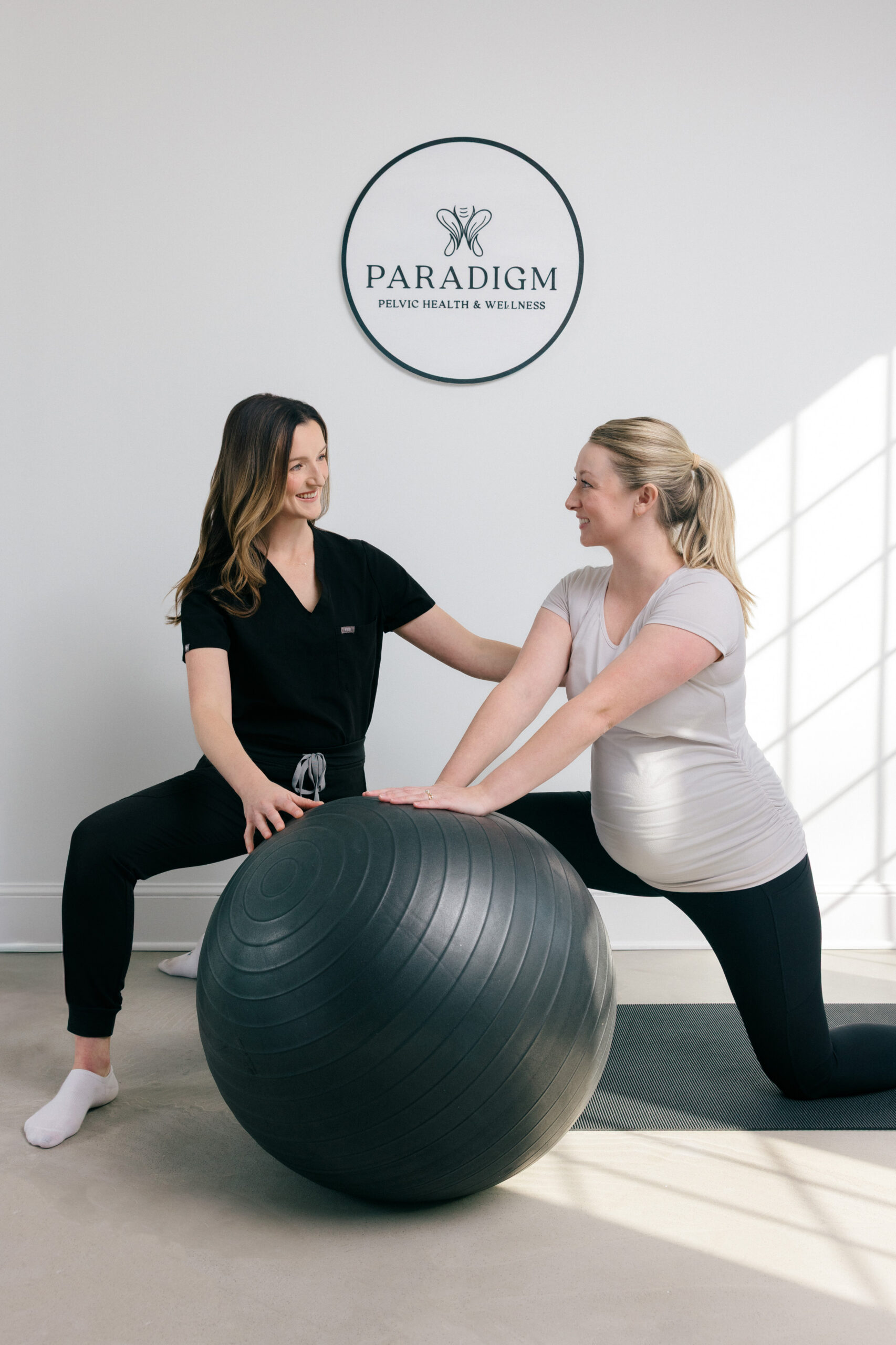 Two women looking at each other one is a therapist the other is a patient learning how to use a rubber ball